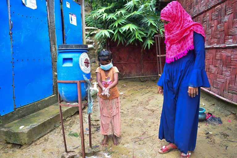 Halima (right) showing her children how to use a hand washing station in her Rohingya refugee camp in Cox’s Bazaar region of Bangladesh in August 2020. Photo credit: Inmanuel Chayan Biswas/Caritas Bangladesh.