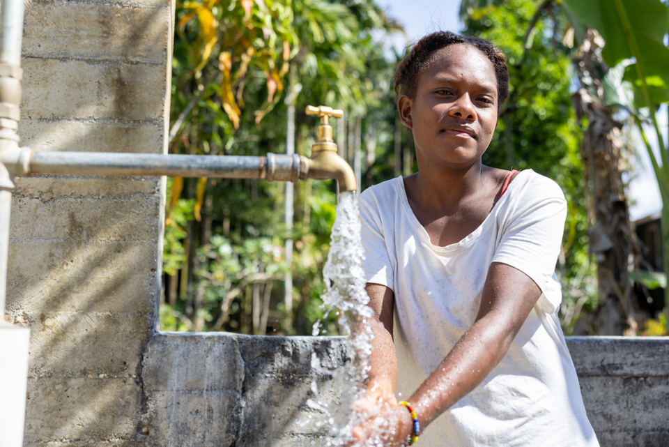 Patricia washing hands using a new water tap outside her home. Photo: Caritas Australia