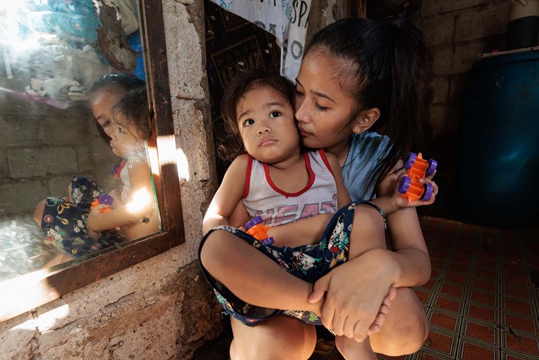 Ronita (22) cuddles Egzy Gray (3) in their small home in Quezon City, Philippines. Photo: Richard Wainwright/Caritas Australia 