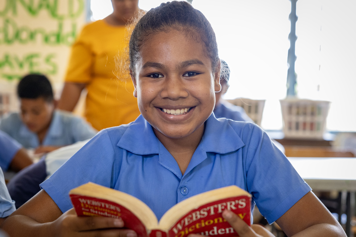 Child is supported by monthly giving reading a book.jpg