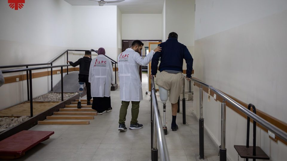 Specialists Assist A Man And A Young Boy As They Relearn How To Walk With Their Artificial Legs Photo Credit Caritas Jerusalem
