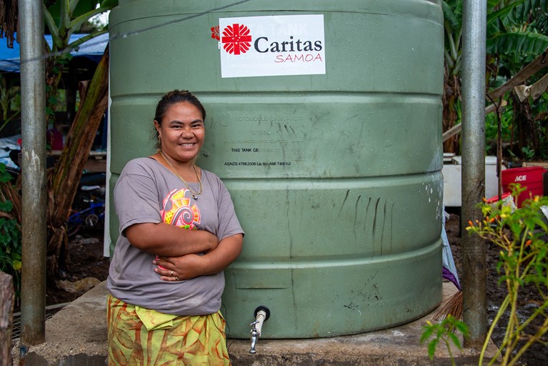 Leaia with her new water tank outside her home. Photo: Laura Womersley/Caritas Australia