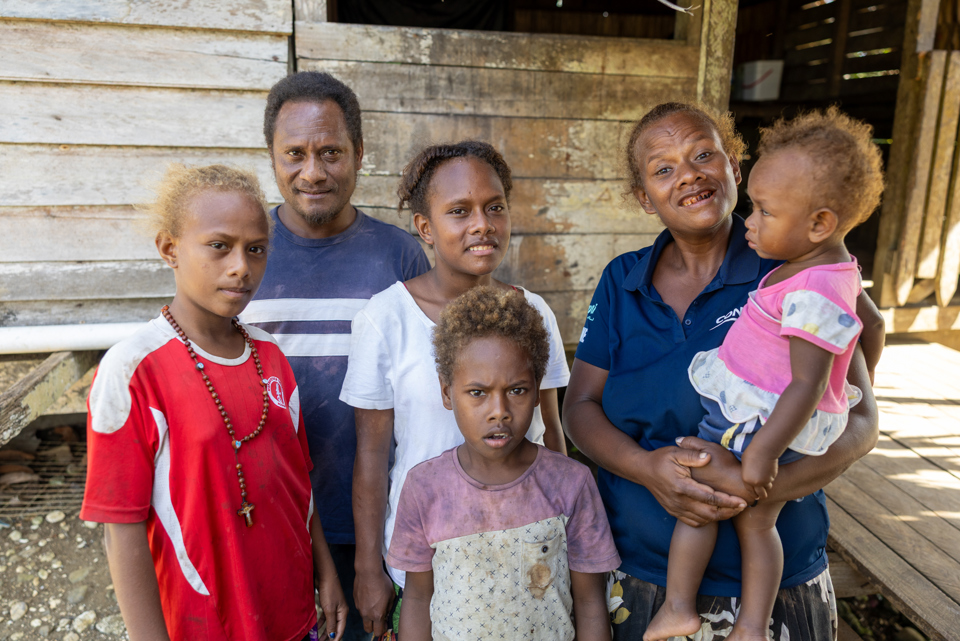 Patricia (centre) with her family outside their family home. Photo: Caritas Australia