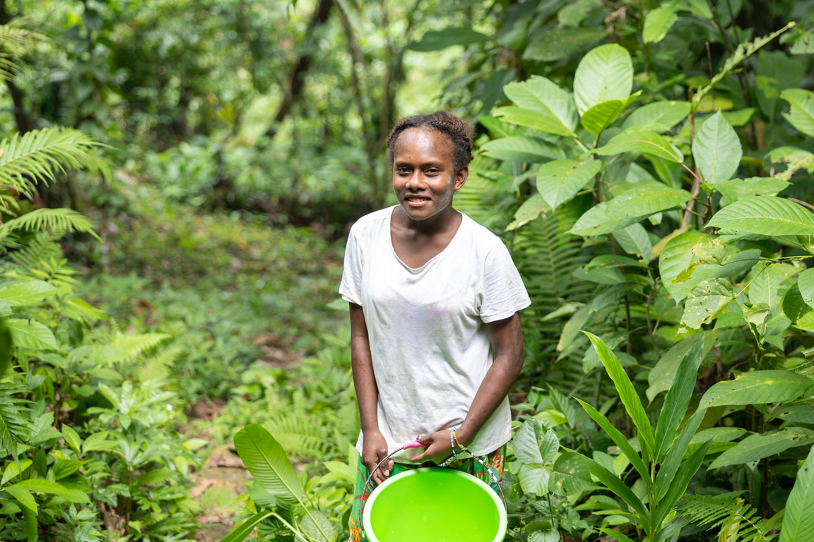 Patricia carrying a bucket of water home to her village in Solomon Islands. Photo: Caritas Australia