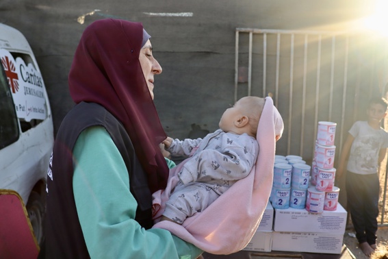 A Caritas Jerusalem Aid Worker Holds A Baby During Distribution Of Life Saving Formula Photo Credit Caritas Jerusalem