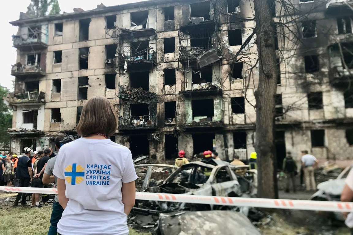 A Caritas Ukraine staff member looks at an apartment block damaged by shelling photo credit Caritas Ukraine.jpg