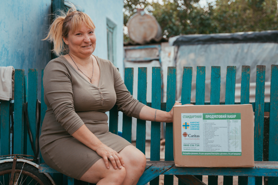 Liudmyla holding a humanitarian aid package from Caritas