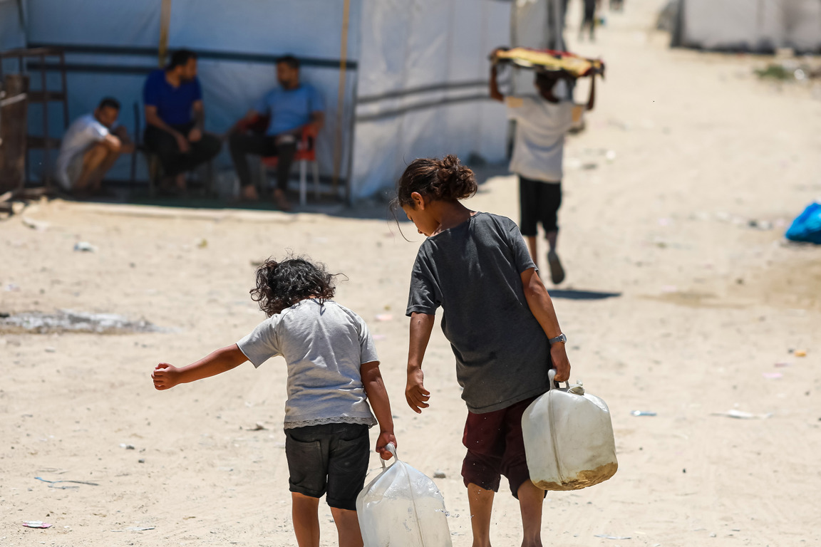 Two small children carry containers photo credit Caritas Jerusalem