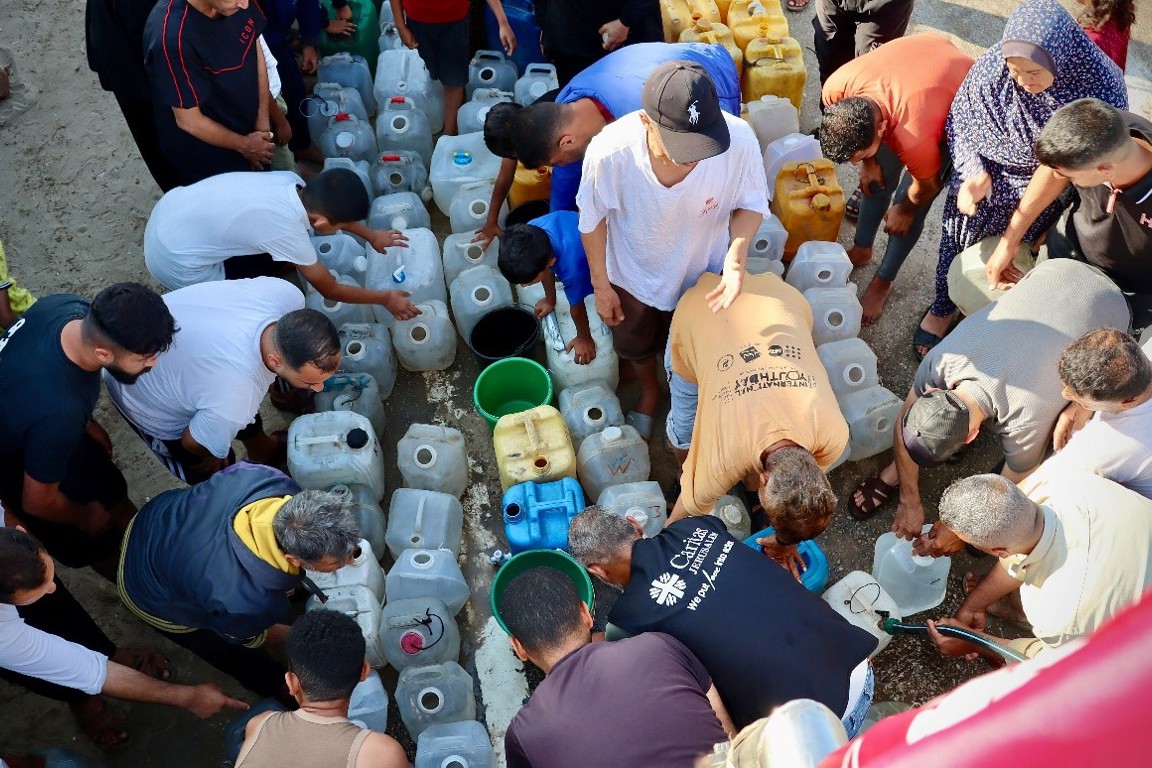 People fill containers from a water trucking site photo credit Caritas Jerusalem.jpg