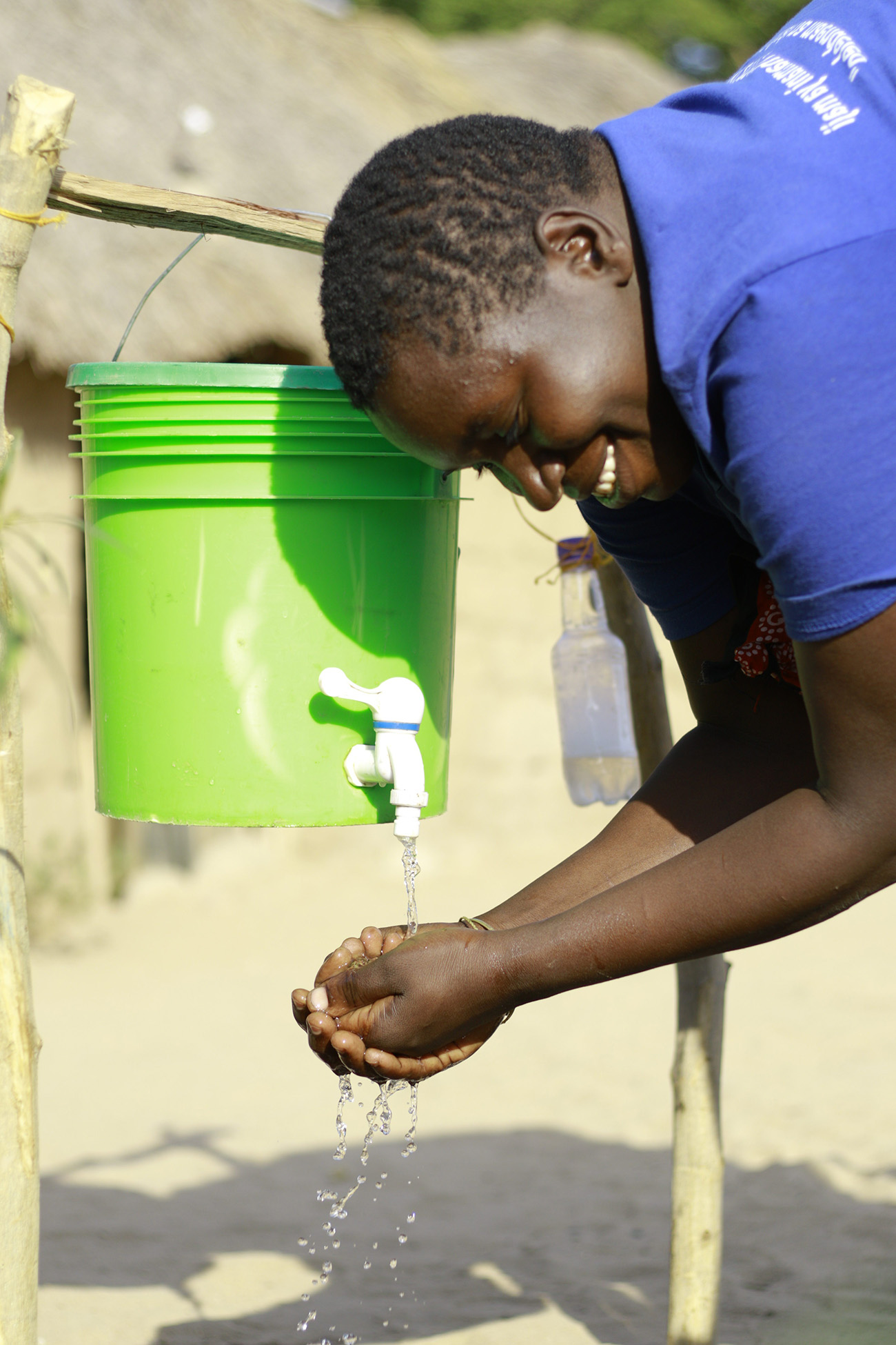 Maria washing her hands using a bucket