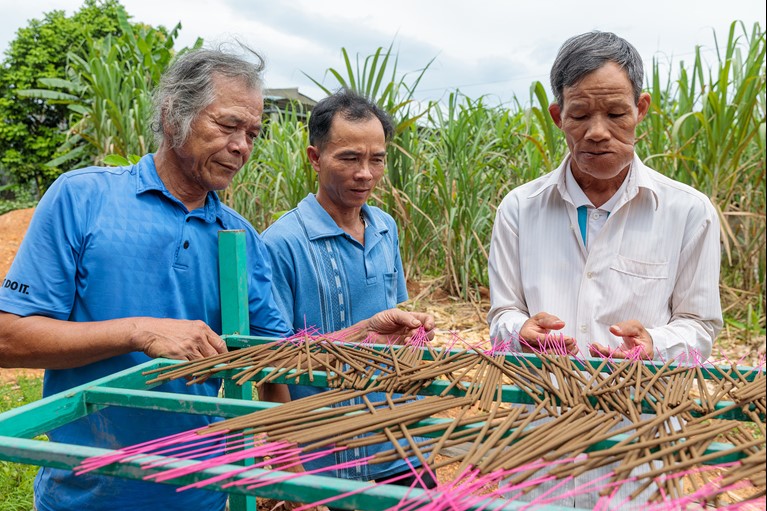 Thu (left) helps make incense sticks with fellow members of his VSLA (Village Savings and Loans Association) group near his home in Quang Tri province. Photo: Phan Tan Lam/Caritas Australia