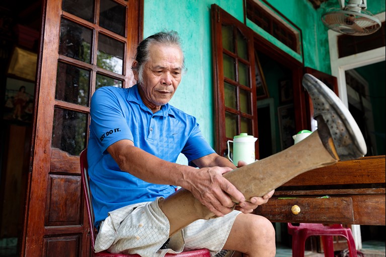 Thu putting on his prosthetic leg at his home in Quang Tri province, Vietnam. Photo: Phan Tan Lam/Caritas Australia