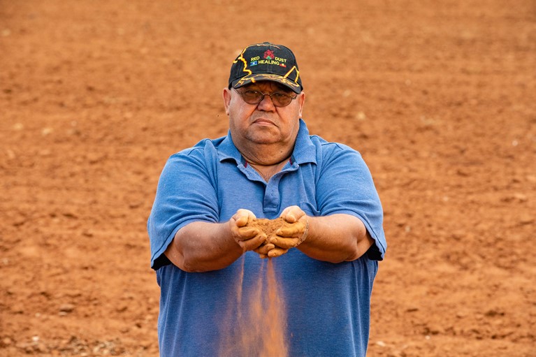 Tom holds red dust near his home town of Narromine, Australia, 2019. Tom is the founder of Red Dust Healing, a specific cultural healing program written from an Indigenous perspective. It aims to engage Indigenous men, women and families to recognise and confront problems, hurt and anger in their lives, stemming primarily from rejection and grief. Photo credit: Richard Wainwright/Caritas Australia.