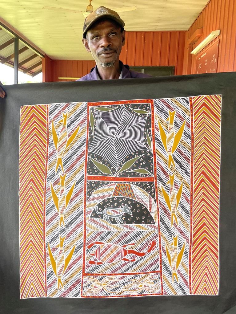 First Nations artist Harry Malibirr holding a painting that depicts five of his dreaming stories. Photo: Djilpin Arts.