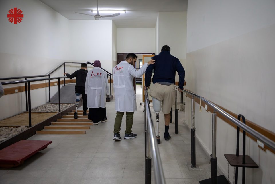 Specialists Assist A Man And A Young Boy As They Relearn How To Walk With Their Artificial Legs Photo Credit Caritas Jerusalem