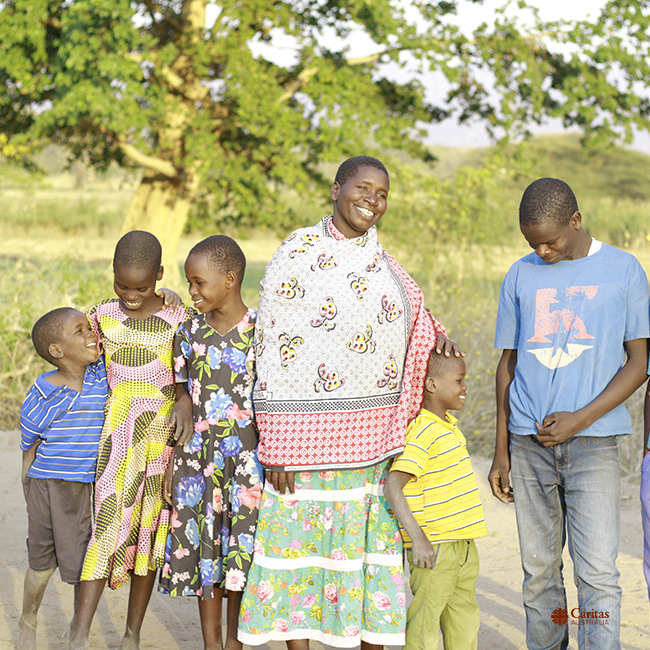 Maria standing with her family near their home in Tanzania. Photo credit: August Lucky/Caritas Australia.