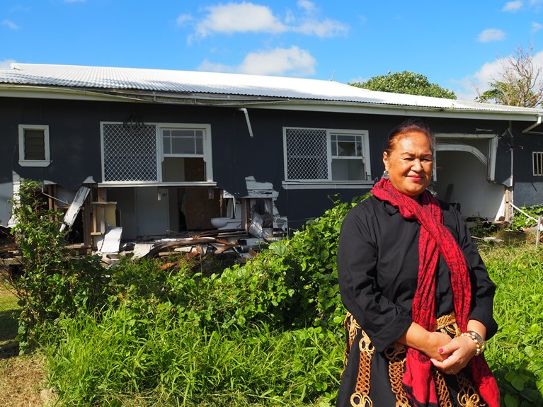 Tupou in front of a destroyed home in Tonga. Photo: Nicole Chehine/Caritas Australia