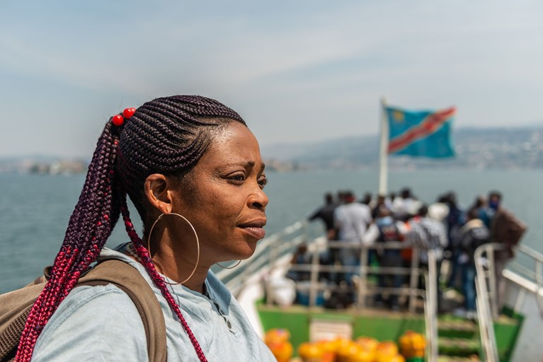Rosalie looks out from the deck of a passenger boat after buying shoes from a market in Goma, eastern Democratic Republic of Congo. Rosalie travels to Goma, the main market town in the region, by boat about twice a month to buy second-hand shoes. Photo: Arlette Bashizi/Caritas Australia 