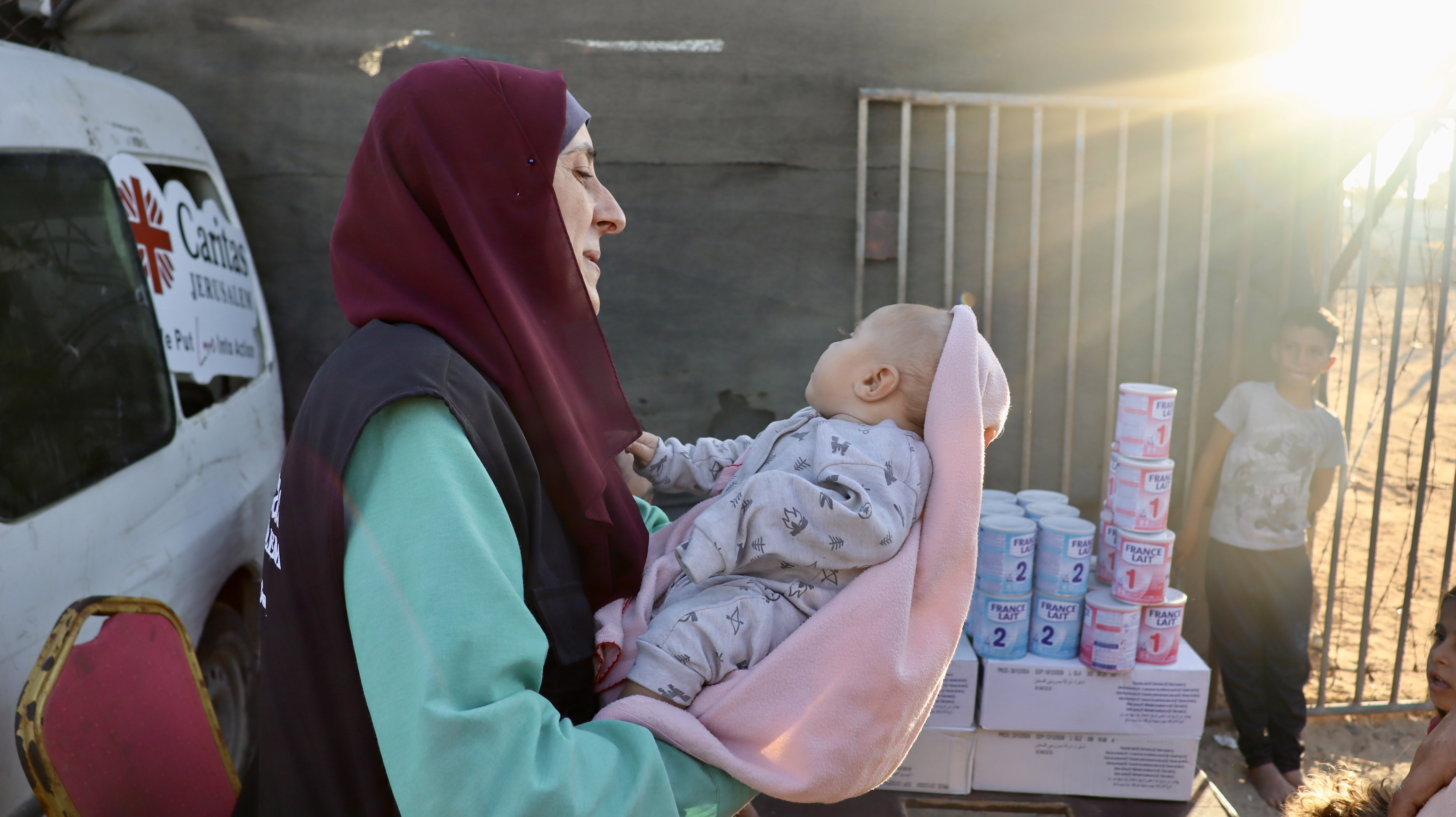 A Caritas Jerusalem Aid Worker Holds A Baby During Distribution Of Life Saving Formula Photo Credit Caritas Jerusalem