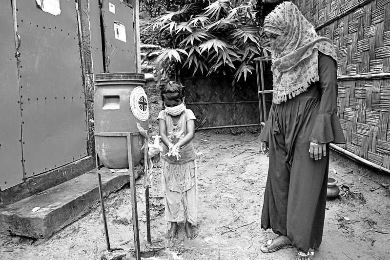 Woman showing her children how to use a hand washing station in Bangladesh