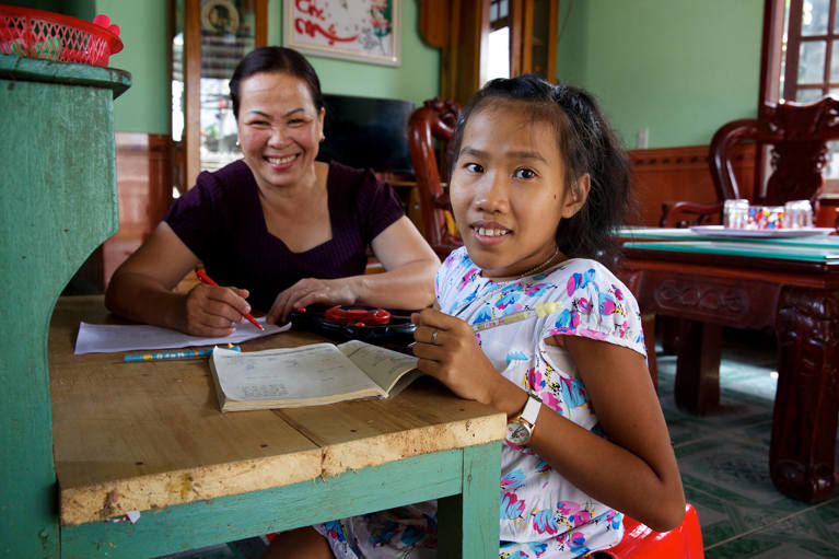 Nguyet from Vietnam during a literacy class with her teacher Quynh. Nguyet was born with cerebral palsy causing paraplegia of her legs and one hand and as a result has been unable to attend school. Photo: Richard Wainwright/Caritas Australia.