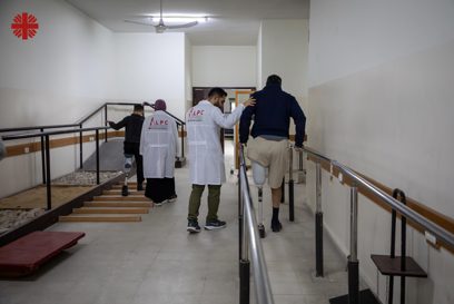Specialists Assist A Man And A Young Boy As They Relearn How To Walk With Their Artificial Legs Photo Credit Caritas Jerusalem