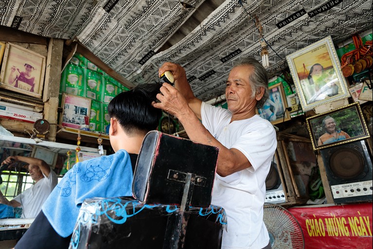 Thu working in his barber shop at his home in Quang Tri province, Vietnam. Thu set up the barber shop after receiving a loan when he joined a local VSLA. Photo: Phan Tan Lam/Caritas Australia
