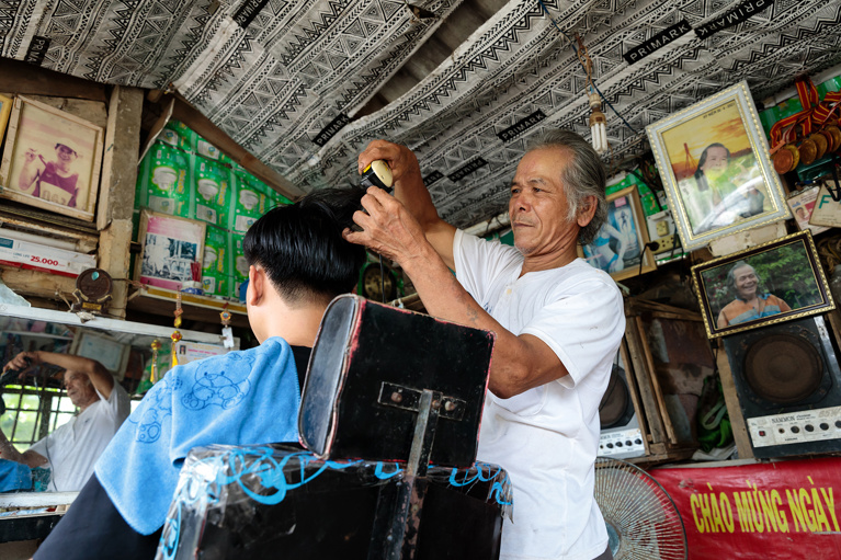 Thu working in his barber shop at his home in Quang Tri province, Vietnam. Thu set up the barber shop after receiving a loan when he joined a local VSLA. Photo: Phan Tan Lam/Caritas Australia