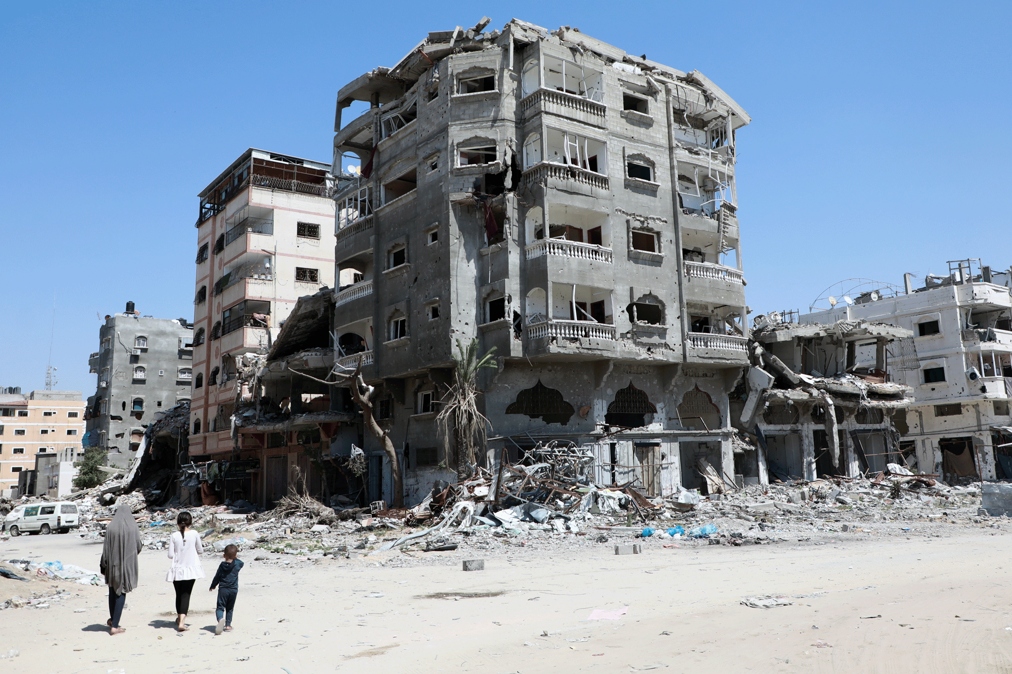 Two Adults And A Child Walk Through Gaza During The Ongoing Devastation